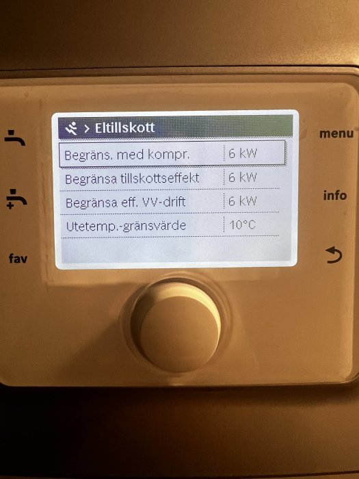 Digital display på en värmepumps kontrollenhet som visar elanvändning och temperaturinställningar.