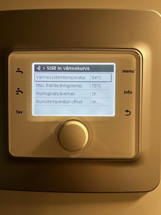 Display av värmepumpens kontrollenhet med inställningar för värme och rumstemperatur-offset.