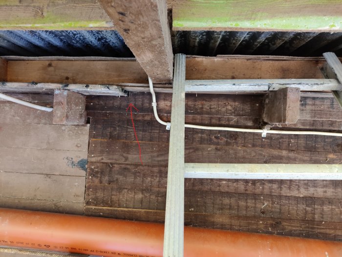 Närbild av ett tak under renovering med synliga reglar och råspont, märkt nivåskillnad på sponten.