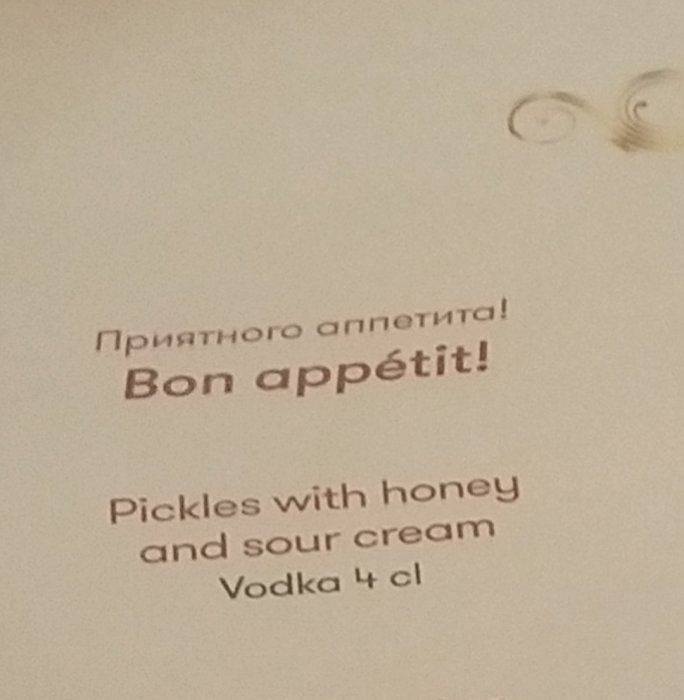 Menytext på flera språk inklusive "Smaklig måltid" och rätten "Pickles with honey and sour cream Vodka 4 cl".