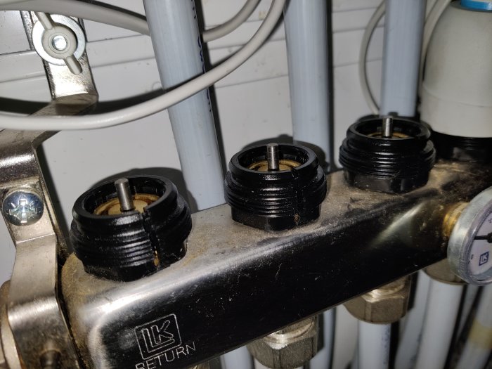 VVS-installation med termostatventiler på en radiator och texten "LK RETURN" synlig på kopplingen.