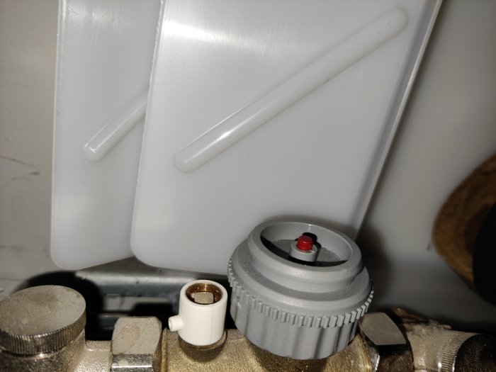 Tryckmätare inställd på ca 0,4 bar med synlig röd indikator, och delar av värmeinstallationen.