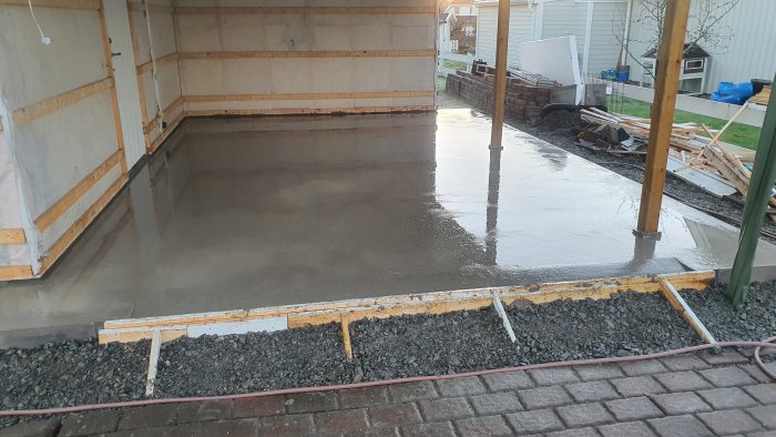 Nyligen gjuten garageplatta med temporära stolpar och takstol.