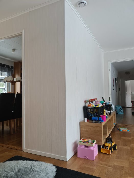 Vägg där murstocken förmodas vara dold, intill leksaker och inredning i ett hem.
