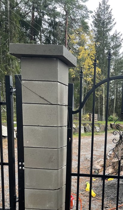 Betongpelare vid gånggrind med förberedelse för handtagsbeslag och två vit pluggar insatta.