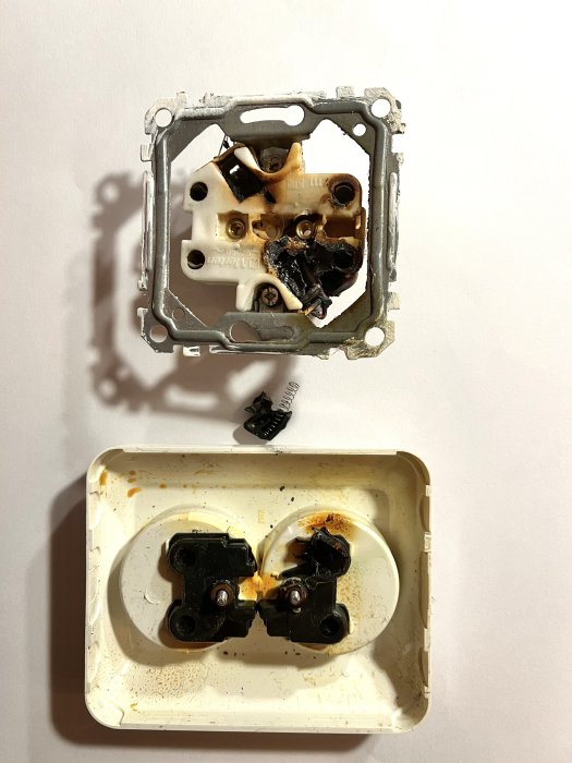 Bränd elektrisk vägguttag och delvis smält anslutningsplast.