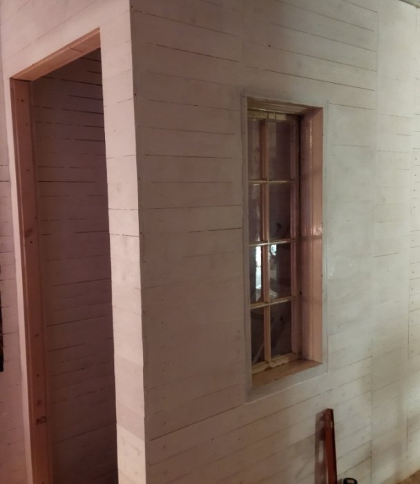 Ett 1850-talsfönster installerat i ett nyligen byggt trapphus med vitklädda träväggar.