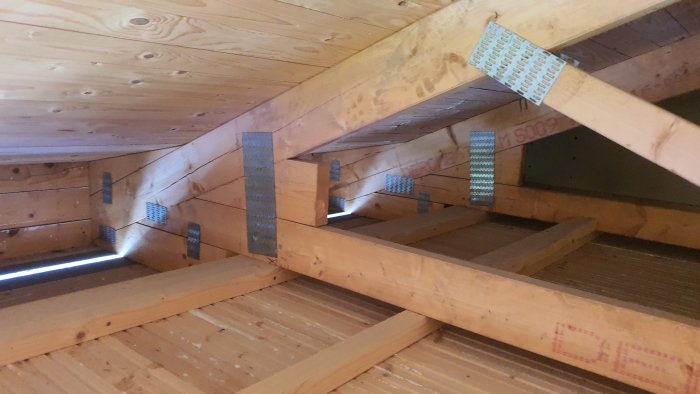 Inre takkonstruktion med takstolar och metallförstärkningar i ett underkonstruktionsstadium.