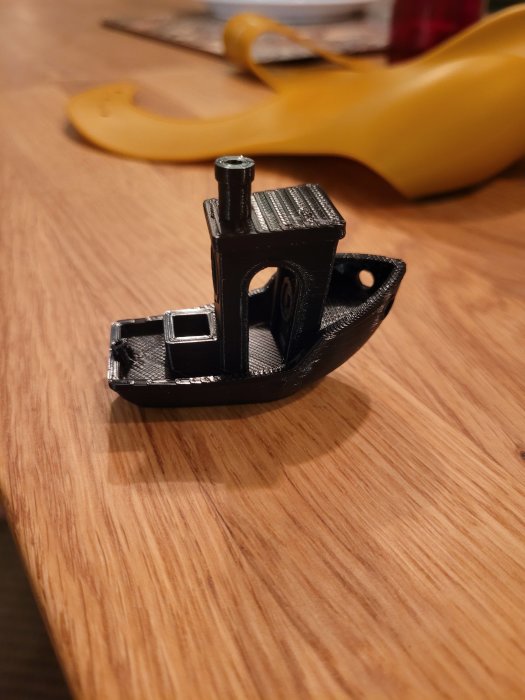 3D-utskriven svart båtmodell på träbord, skapad med 3dprimas filament.