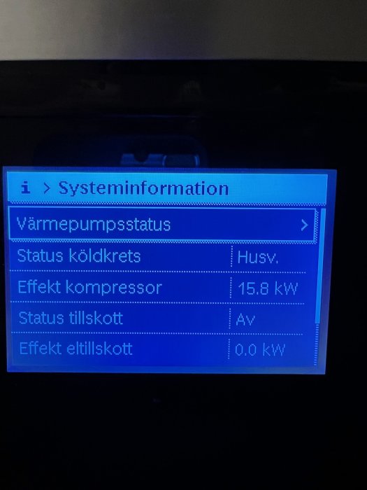 Värmepumpens digitala display som visar systeminformation med kompressoreffekt på 15,8 kW och tillskott värmeeffekt på 0 kW.