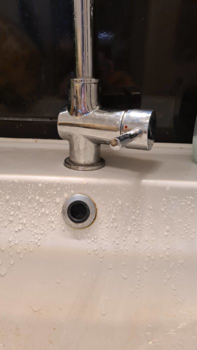 Löst sittande badrumsblandare på handfat med droppar av vatten runt omkring.
