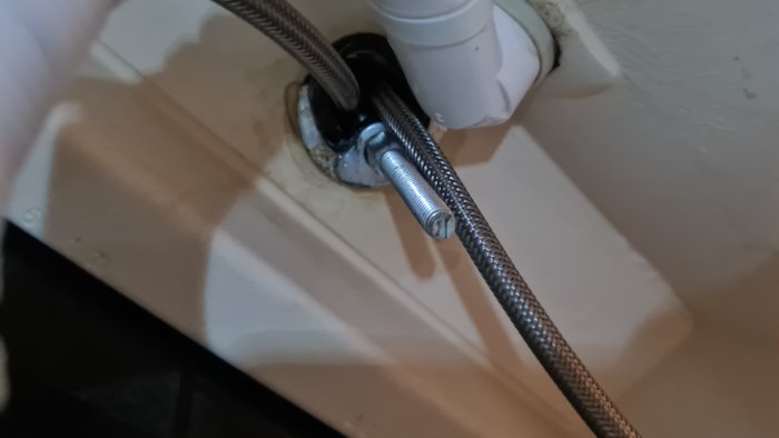Löst sittande blandare med exponerad mutter och flexibla rör i radhusbadrum.