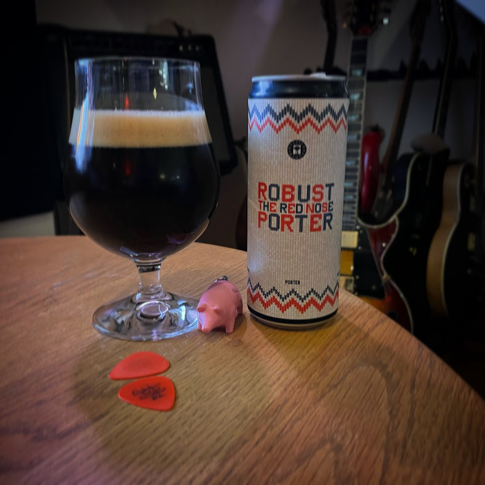Ölglas med mörkt öl bredvid burk märkt "Robust The Rednose Porter", gitarrer i bakgrunden.