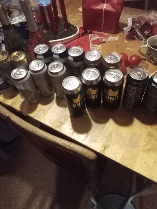 Flerradigt arrangemang av ölburkar på ett bord med en julstjärna och tomater i bakgrunden.