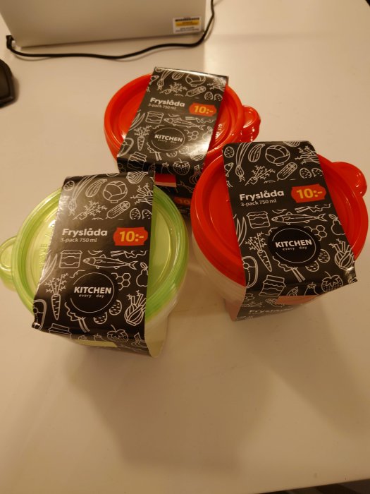 Tre förpackade plastlock med tillhörande genomskinliga behållare på ett köksbord, märkta "Fryslåda 3-pack 750 ml".