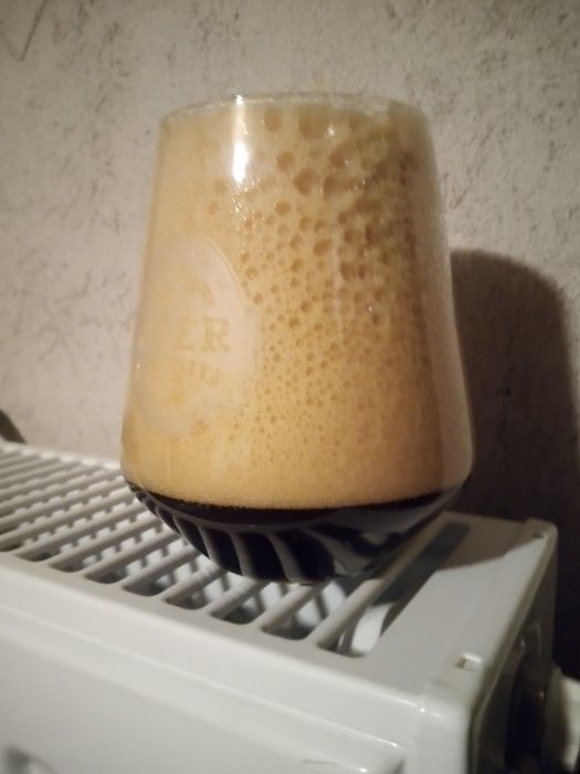 Ölglas överfyllt med skum står på en radiator, problem med att hälla öl från fat.