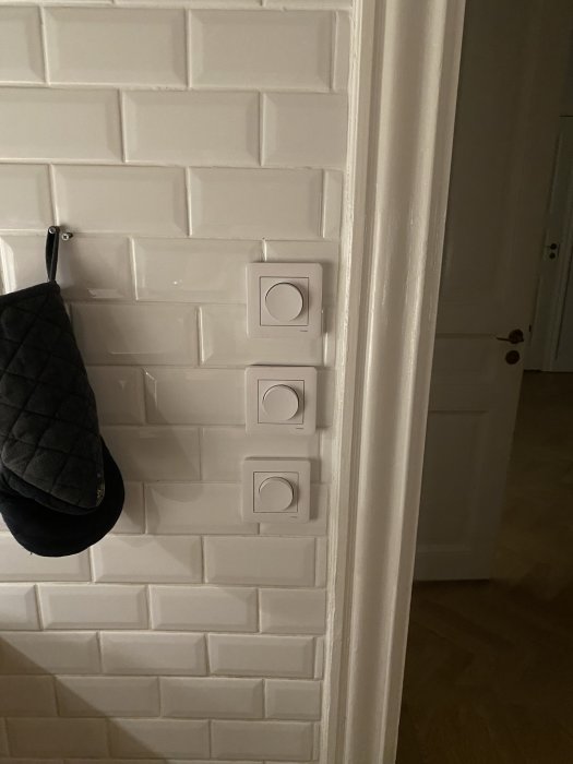 Tre ojämnt placerade vita dimmers mot kaklat köksvägg, ej i lod eller i samma ram.