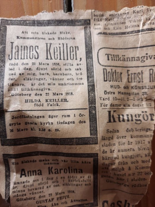 Gammalt tidningspapper från 1918 med dödsruna över industrimannen James Keiller på ett trägolv.