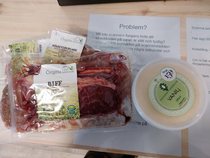 Förpackade lokalproducerade livsmedel inklusive ryggbiff, högrevsburgare och vaniljglass på ett bord.