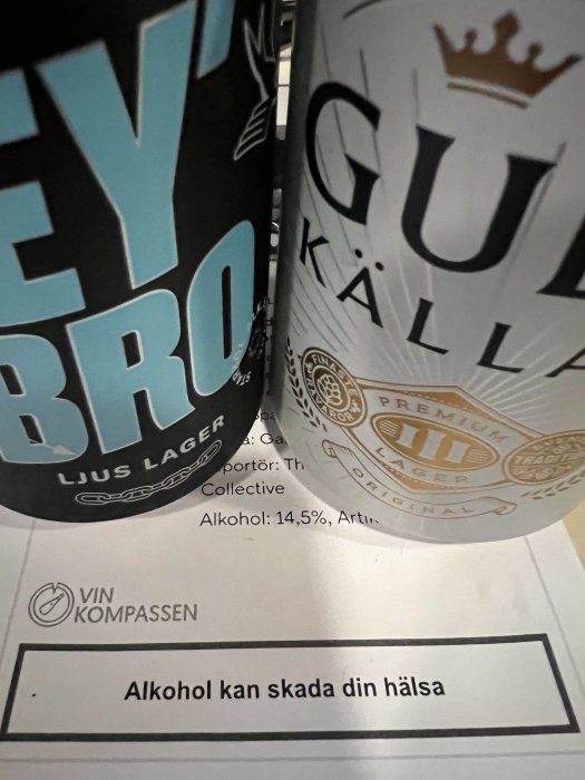 Två ölburkar nära en broschyr med texten "Alkohol kan skada din hälsa".