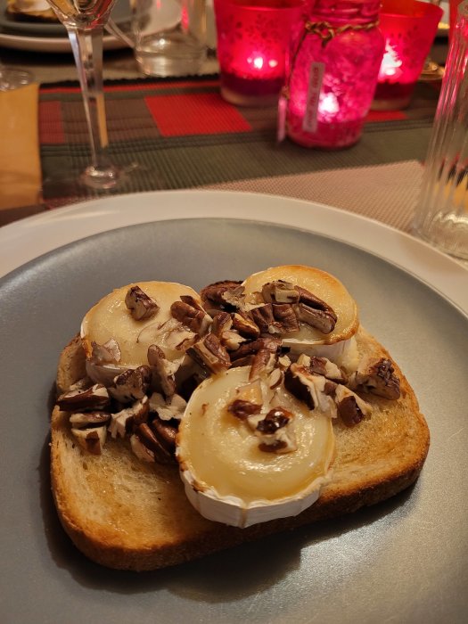 Toast med chevrè och pekannötter på en tallrik, festlig dukning i bakgrunden.