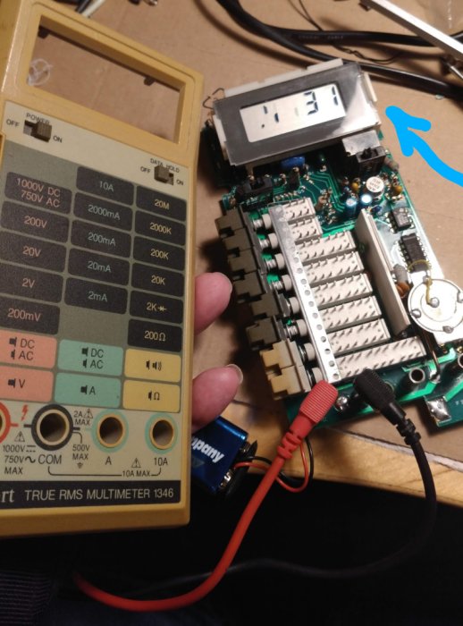 Delvis isärmonterad multimätare med trasig display och testkablar anslutna, vid reparation på ett bord.