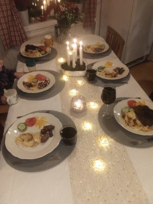 Dukat middagsbord med tända ljus och tallrikar med diverse maträtter och dryck.