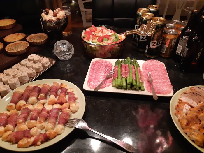 Buffébord med diverse maträtter inklusive sallad, rulltårtor, baconinlindade delikatesser och skivad chark.