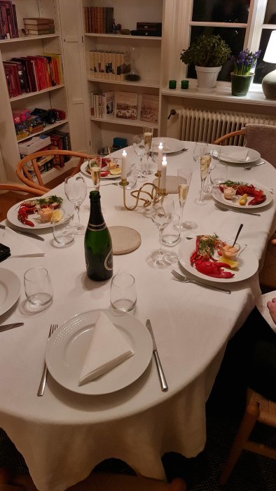Hummer på en väldekorerad middagsbord med tända ljus och en flaska champagne.