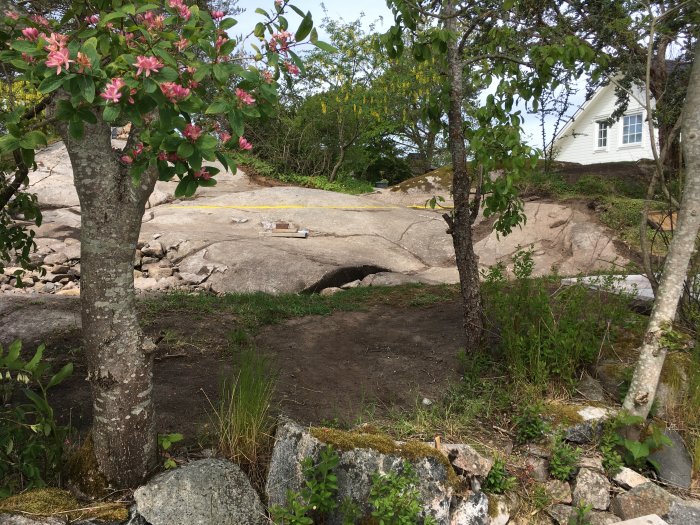 Plats för byggprojekt Attefallshus på kuperad tomt, med markarbeten påbörjade på solid granit, nära befintligt hus.