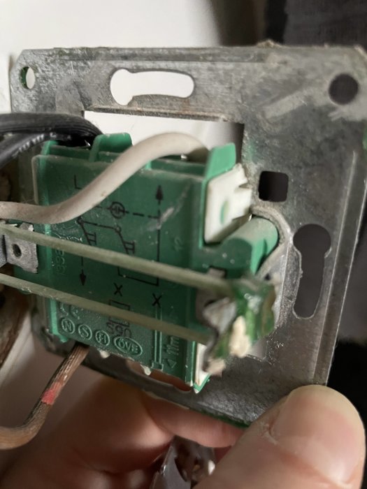 Närbild på en öppen ljusbrytare med synlig elektronik och ledningskopplingar i en vägg.