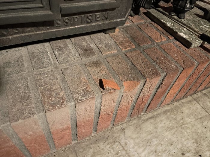 Skadat tegel vid kamin med en 3x4 cm stor bit som lossnat på golvet.