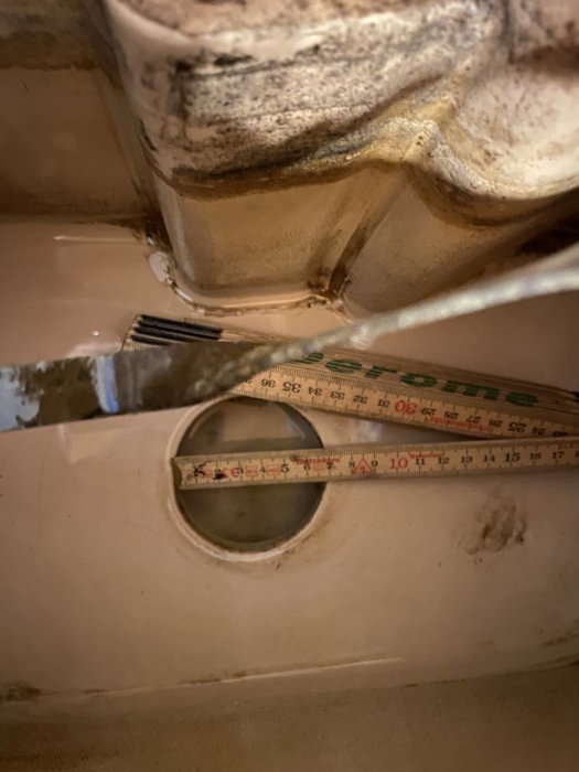 Måttband visar storleken på en gammal toastolens bottenventilsöppning, med märkningen "Royal Sphinx".