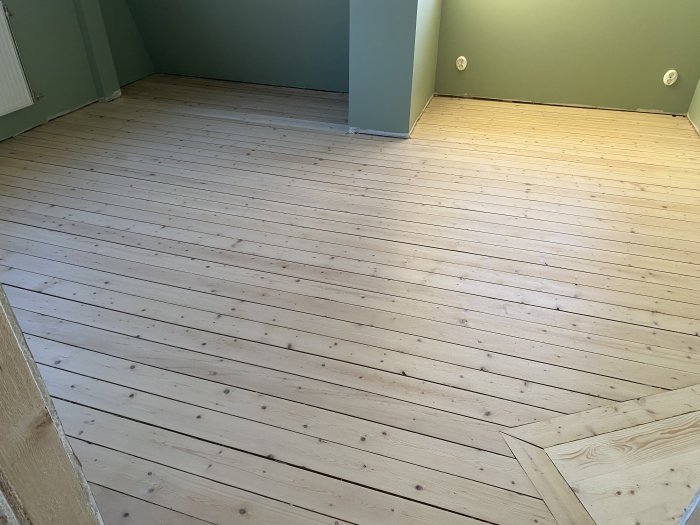 Golv i litet rum efter slipning, med ljusat trä och synliga kvistmärken, ojämn färgnyans.