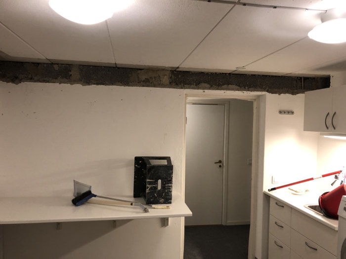 Renoveringsarbete i kök med borttaget takmaterial som avslöjar betong och balkar.