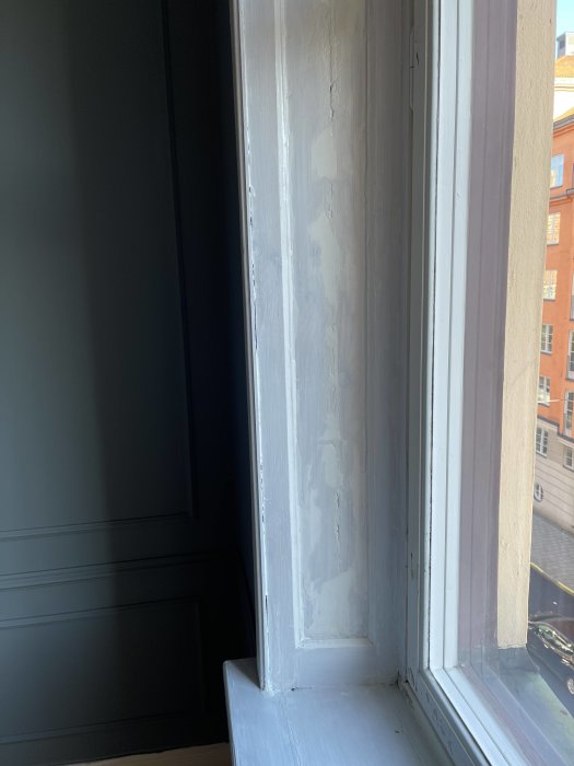 Sekelskiftesfönster under renovering, med borttagen färg och slipade ytor nära fönsterglaset.