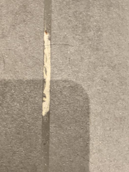 Vit beläggning på fog mellan klinkerplattor, misstänkt kalkutfällning på ett grått klinkergolv.