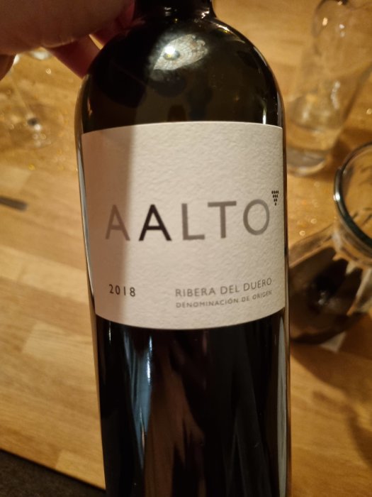 Hand håller en flaska Aalto-vin årgång 2018 från Ribera del Duero, en tradition på nyårsafton.