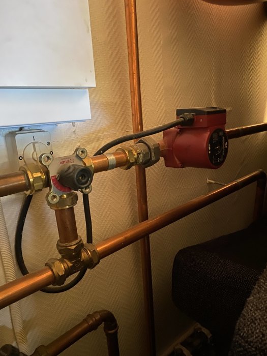 Kopparledningar med röd cirkulationspump och reglerventiler före installation av golvvärme.