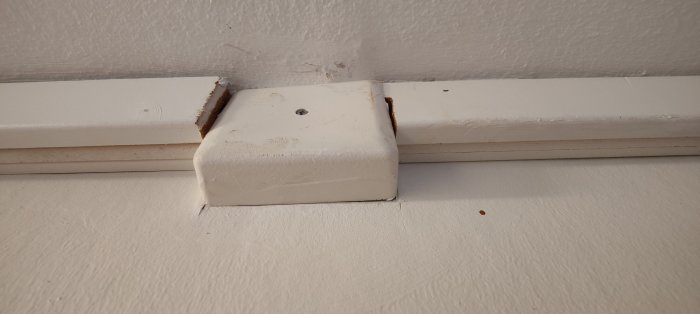 Gammal elinstallation med plastlist och klammad kabel i skarven mellan tak och vägg.