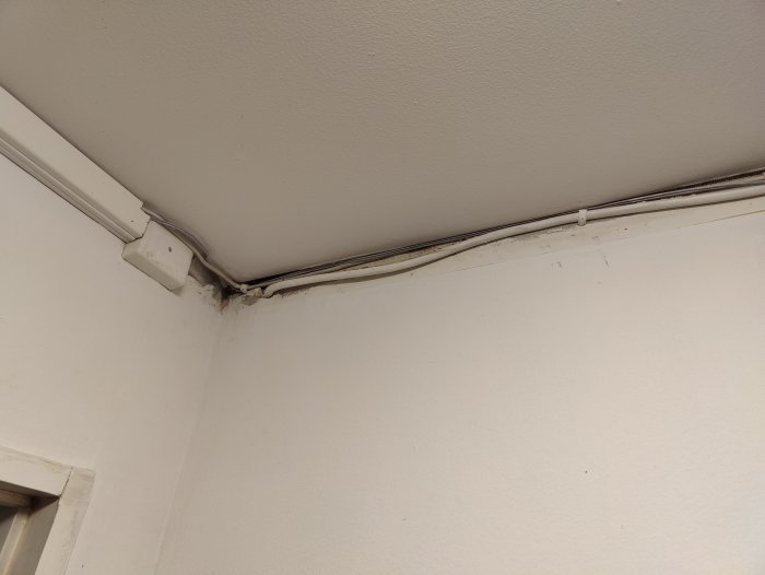 Elektriska kablar klamrade längs en hörna mellan en vägg och tak i ett renoveringsprojekt.