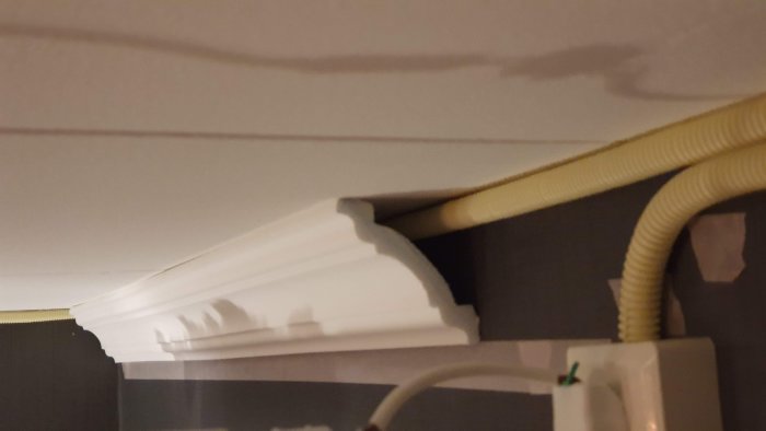 Renoverad hall med ny elinstallation där gul EK-kabel går i flexrör längs vägg täckt av dekorlist.