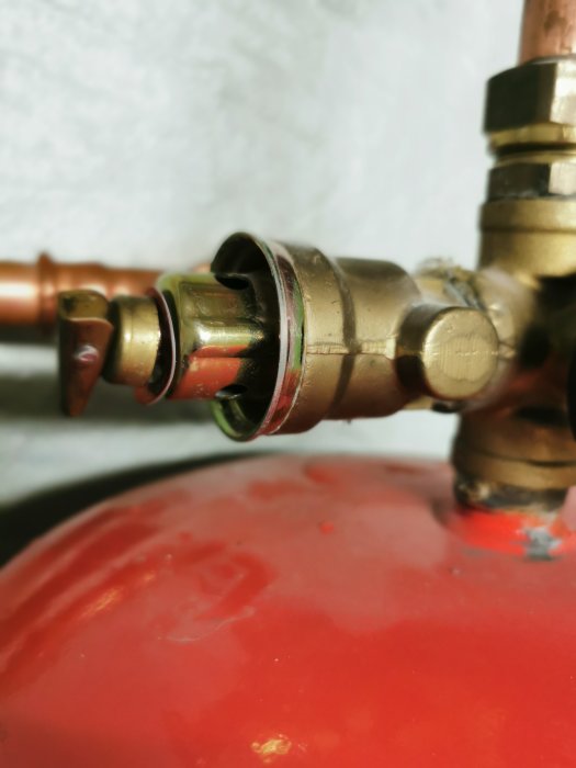 Närbild av ett dräneringsrör på ett tryckkärl från en bergvärmepump, vattendroppar syns.