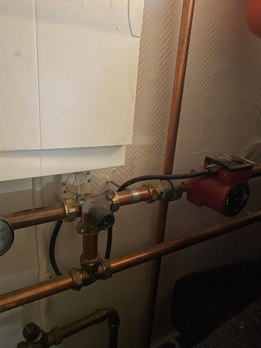 Värmepumpsinställning med cirkulationspump och rörledningar för golvvärmefördelning.