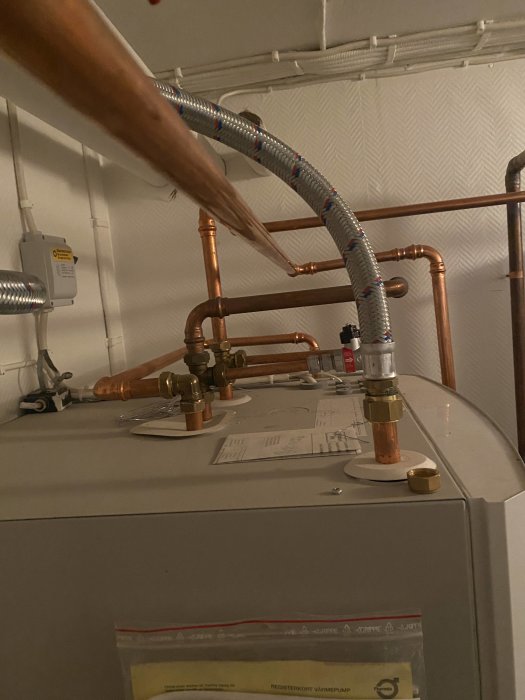 Värmepump och kopparledningar med en cirkulationspump och skrot i bakgrunden.