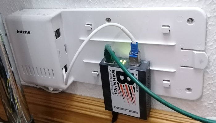 Vit WiFi-router på vägg med ansluten Ethernet-kabel och Bahnhof-internetmodem.