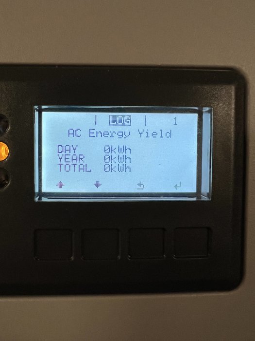 Display på en energimätare som visar AC Energy Yield med dags-, års- och totaldata samt tre otryckta knappar under.