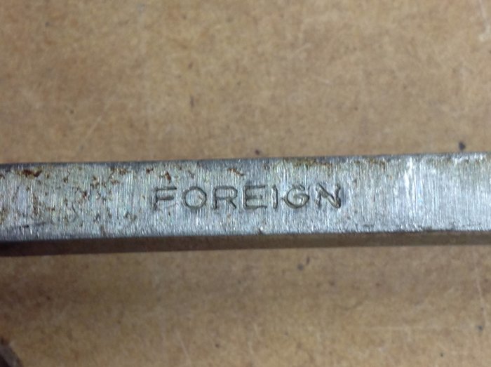 Begagnat stämjärnsblad med ordet "FOREIGN" präglat på metallen.