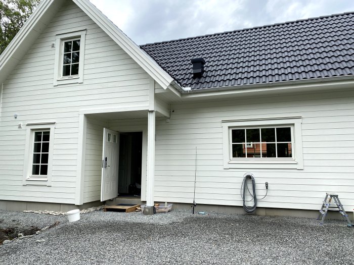 Nytt vitmålat sommarhus från Landsbrovillan med snedtak och entré under tak.