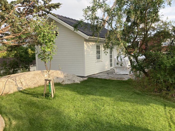 Nyrenoverad husfasad med gräsmatta och trädgård, klar efter 5 veckors arbete.